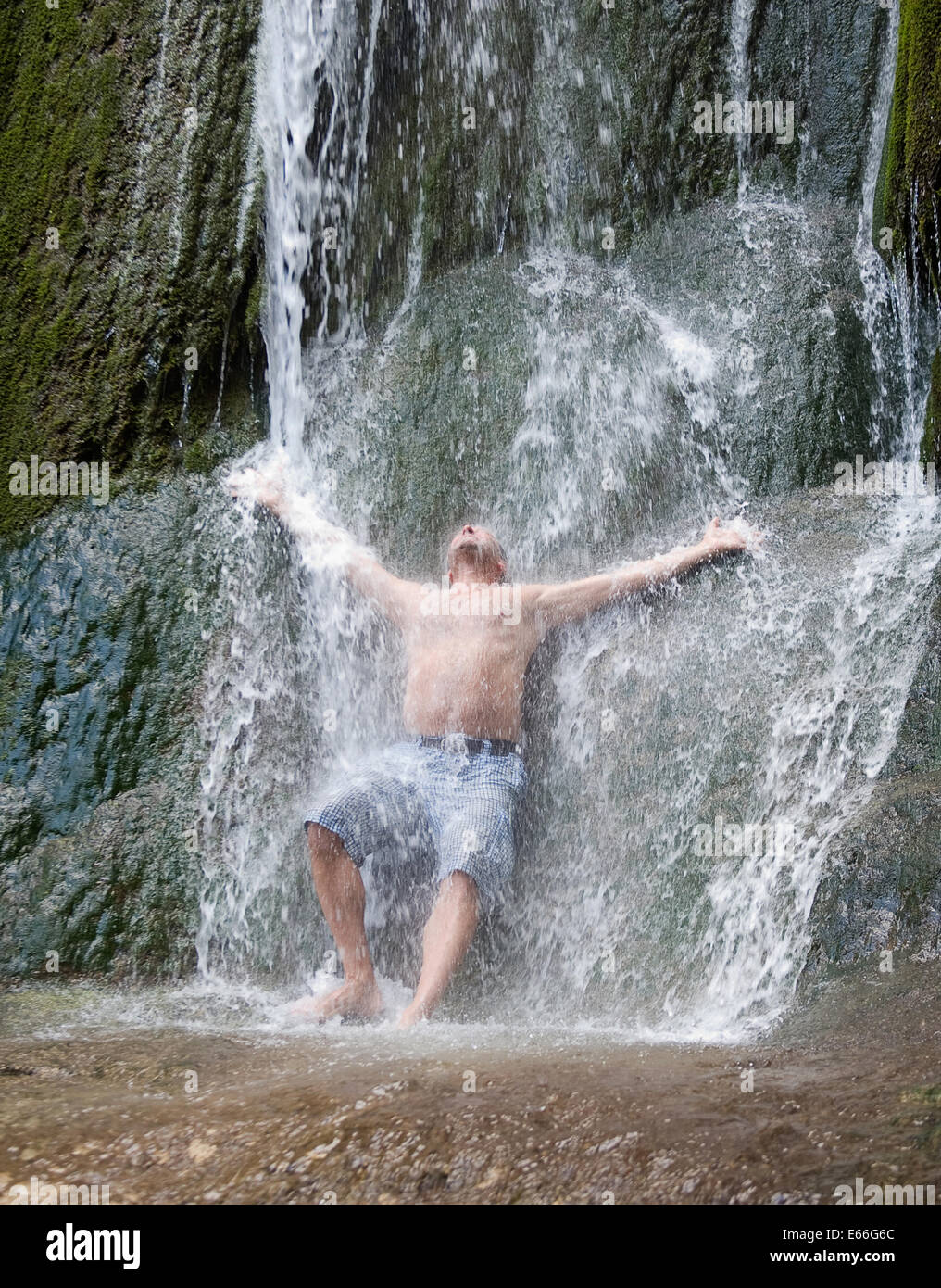 A man is having a shower underneath a natural waterfall Stock Photo