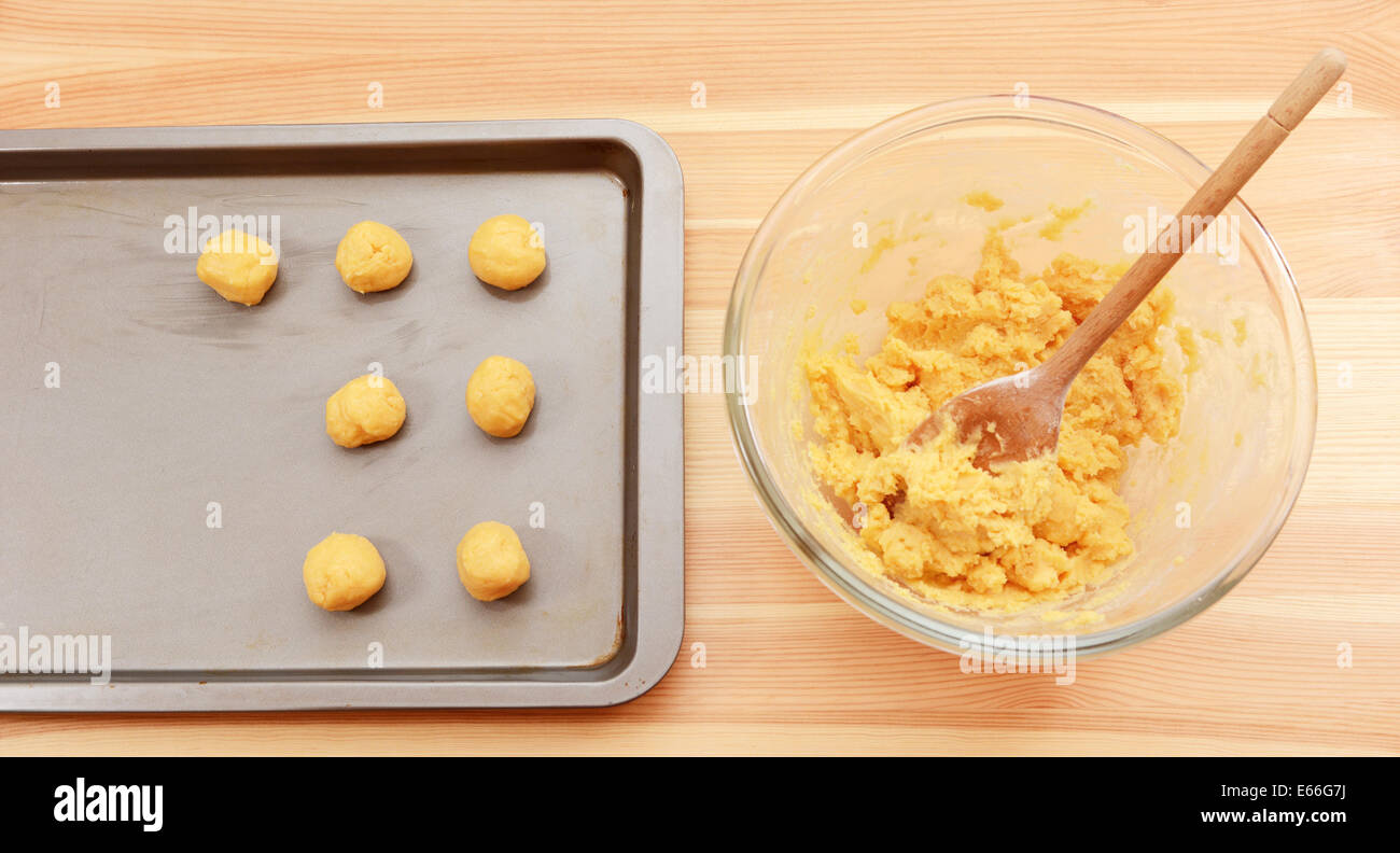 Adding balls of cookie dough to a baking sheet from a bowl of raw mixture Stock Photo