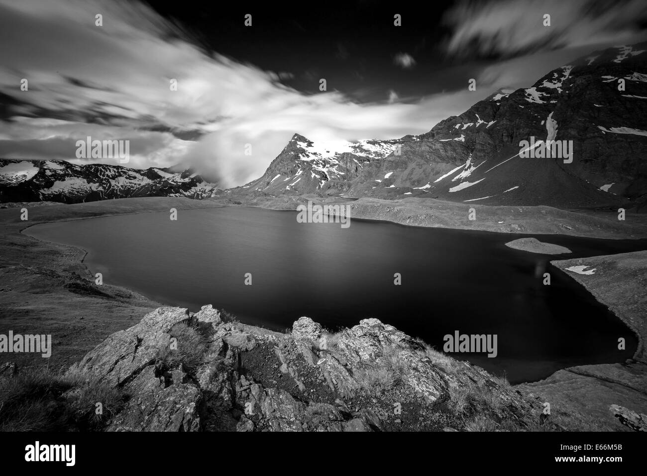 Sunlight and cloudy sky on lake Rosset. The Gran Paradiso National Park. Valle d'Aosta. Italian Alps. Europe. Black White mountain landscape. Stock Photo