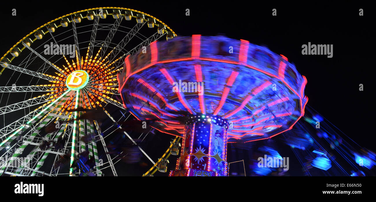 Herne, Germany. 9th Aug, 2014. Visitors sit in an illuminated chairoplane next to a ferris wheel at the Cranger fun fair in Herne, Germany, 9 August 2014. Photo: Caroline Seidel/dpa/Alamy Live News Stock Photo