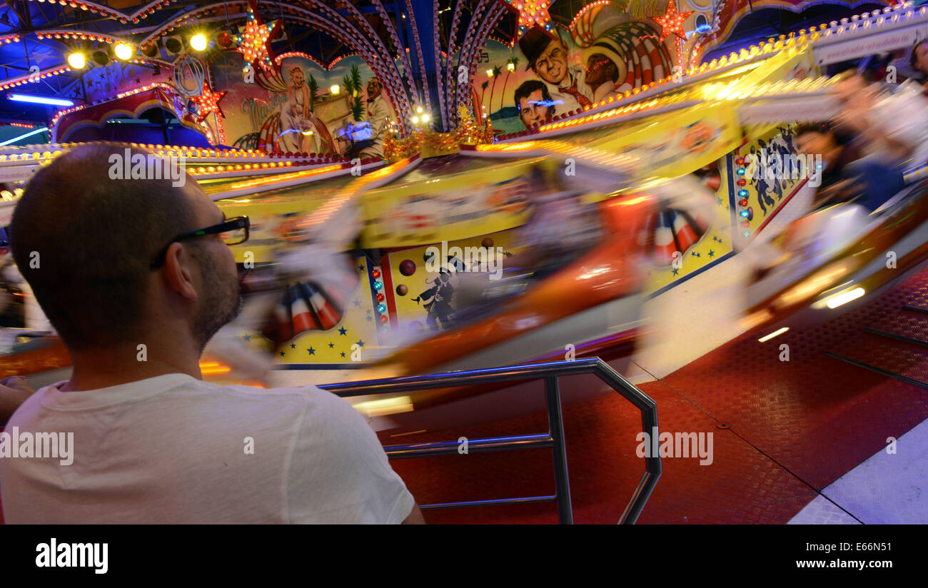 Herne, Germany. 9th Aug, 2014. A visitor looks on at a fast turning merry-go-round at the Cranger fun fair in Herne, Germany, 9 August 2014. Photo: Caroline Seidel/dpa/Alamy Live News Stock Photo