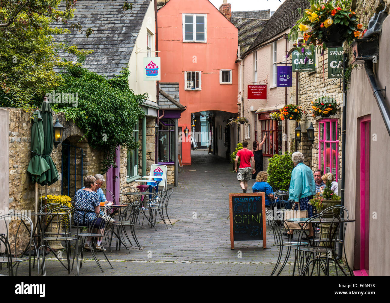 People, cafes and tourist shops in a quaint side steet of Cirencester town, Cotswolds, Gloucestershire, England, UK. Stock Photo