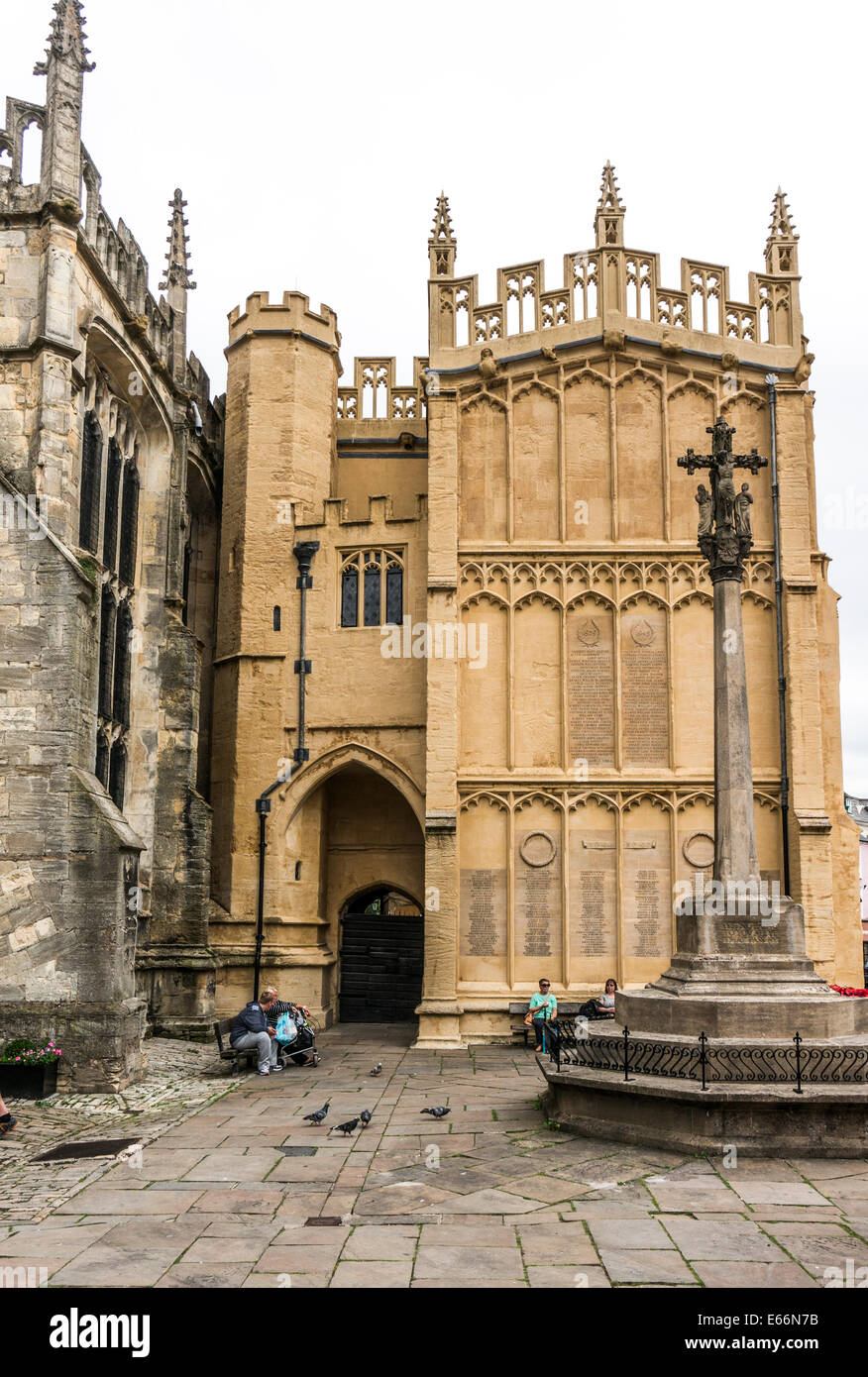 15th century south porch of the historic Church of St John Baptist, with people sitting outside, Cirencester, Cotswolds, Gloucestershire, England, UK. Stock Photo