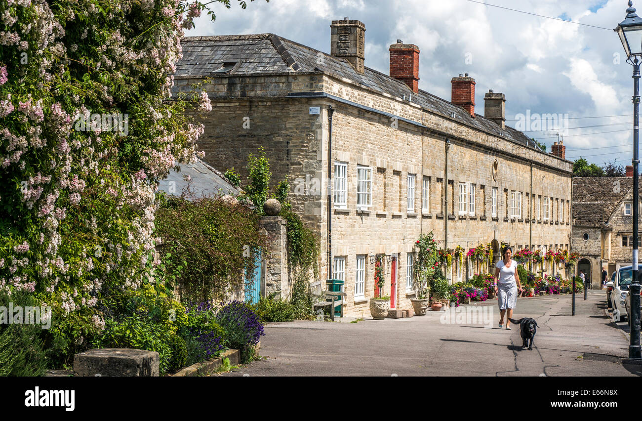 Woman walking her dog by period houses in the parade of Tontine Buildings, Cecily Hill, Cirencester, Cotswolds, Gloucestershire, England, UK. Stock Photo