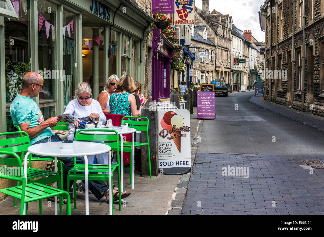 People sitting outside a cafe restaurant in a side street of shops in Cirencester town centre, Cotswolds, Gloucestershire, England, UK. Stock Photo