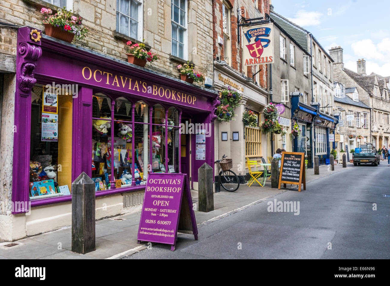 Octavia's Bookshop painted a vivid purple, alongside other shops in a side street of Cirencester town centre, Cotswolds, Gloucestershire, England, UK. Stock Photo