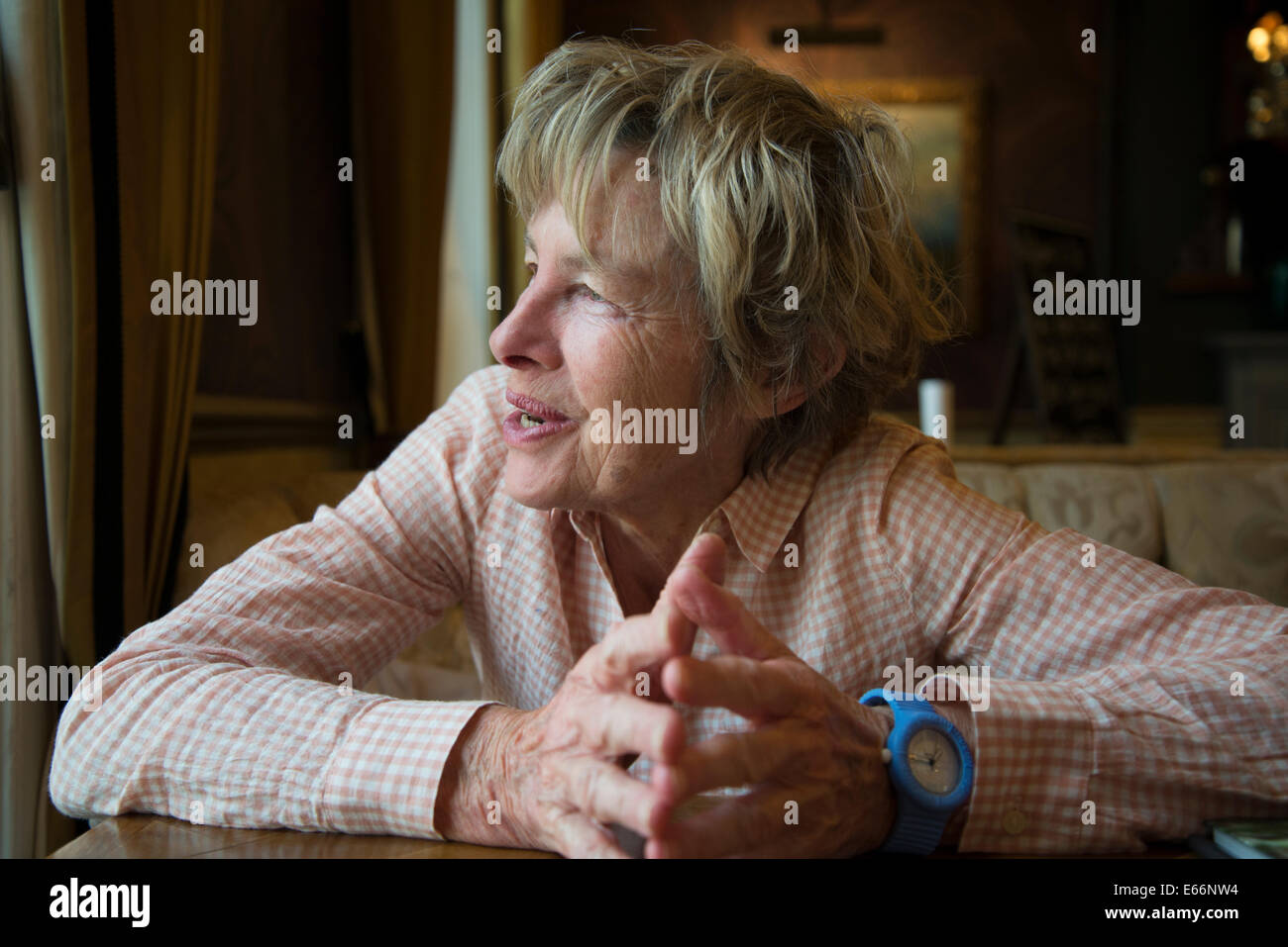 Elderly woman looking out of the window smiling Stock Photo