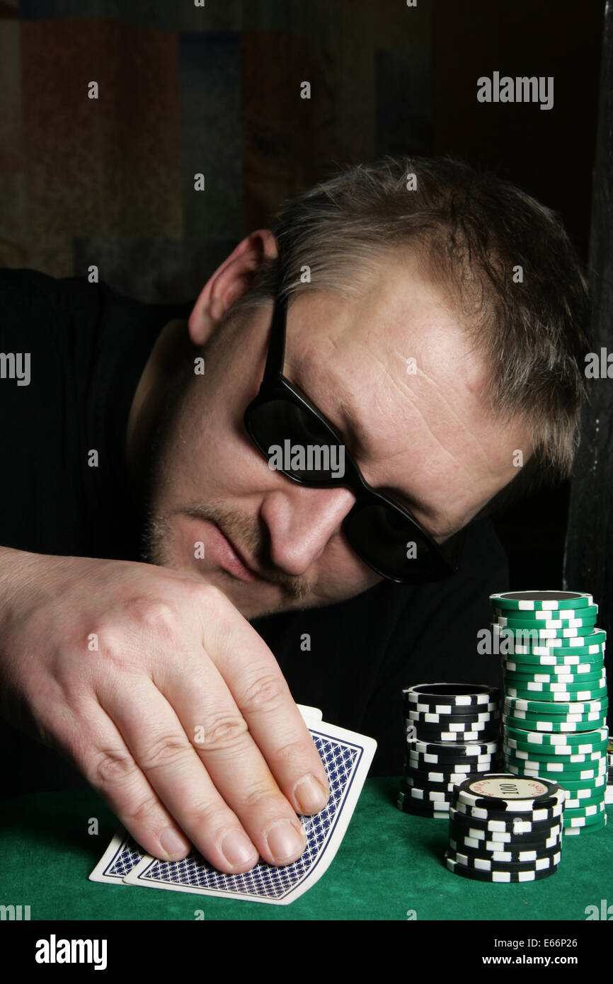 Poker gambler with sun glasses close-up. Focus on the hand and chips. Stock Photo