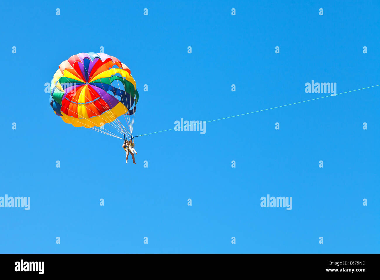 people parascending on parachute in blue sky in summer day Stock Photo