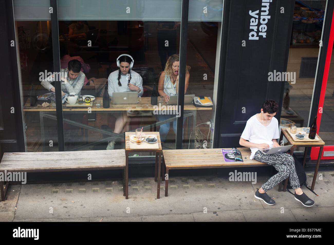 Old Street . Timber yard café seen from the top of a bus with young people using mac laptops Stock Photo