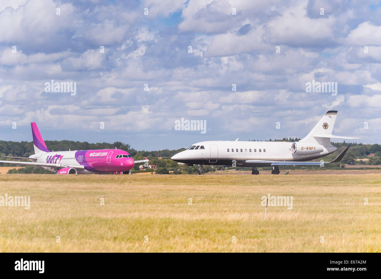 A plane Dassault Falcon 2000EX (G-WWFC) taking off from Luton Airport with Wizzair behind in England , Britain , Uk Stock Photo