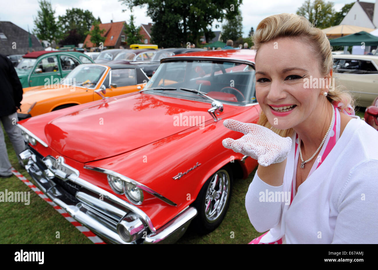 Rastede, Germany. 17th Aug, 2014. Sonja in a 50s dress presents the US car Dodge Coronet from 1959 at the 8th vintage car meeting for cars and motorcycles in Rastede, Germany, 17 August 2014. Photo: Ingo Wagner/dpa/Alamy Live News Stock Photo