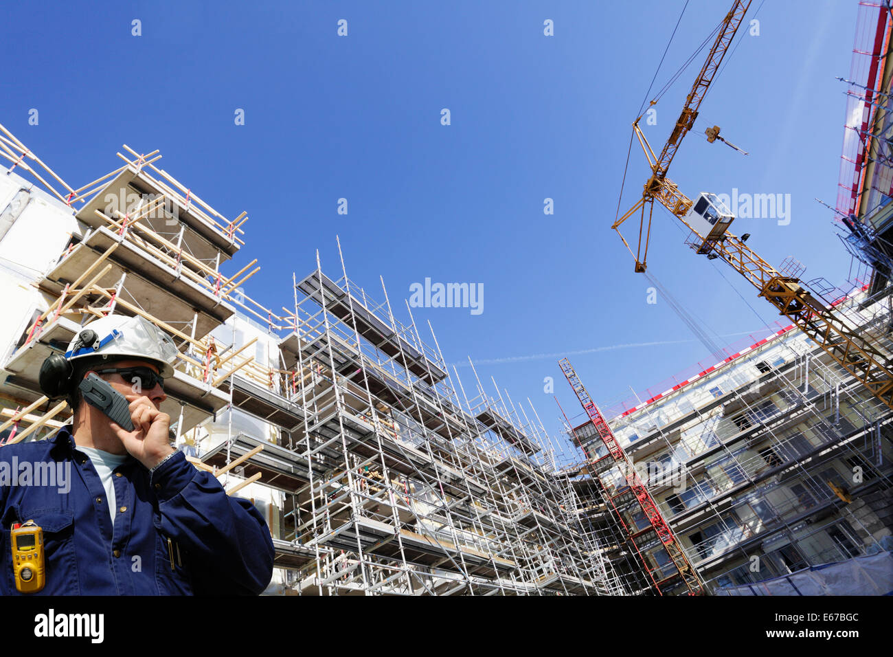 building worker inside construction site, cranes and scaffolding Stock Photo