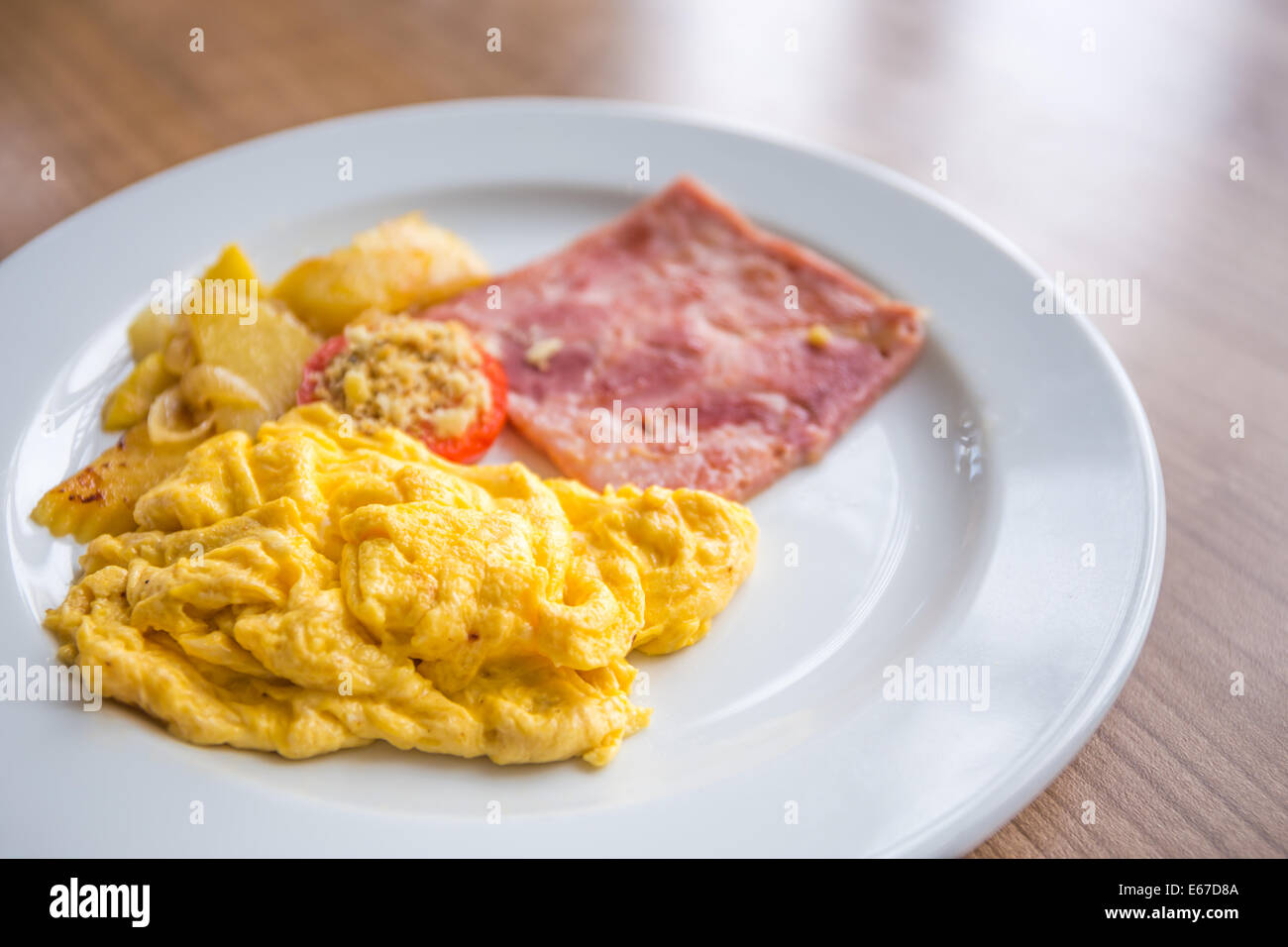 Breakfast with scrambled eggs, slice pork ham, tomato, and potato Stock Photo