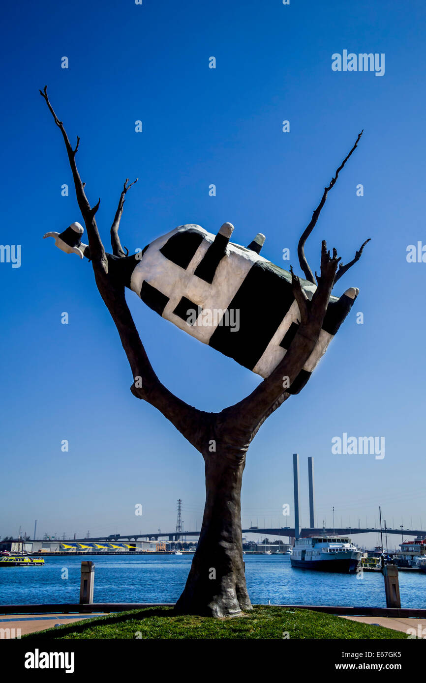 Cow up a Tree Black & white upside down cow in tree sculpture in Docklands Melbourne with Bolte Bridge in background, Australia Stock Photo