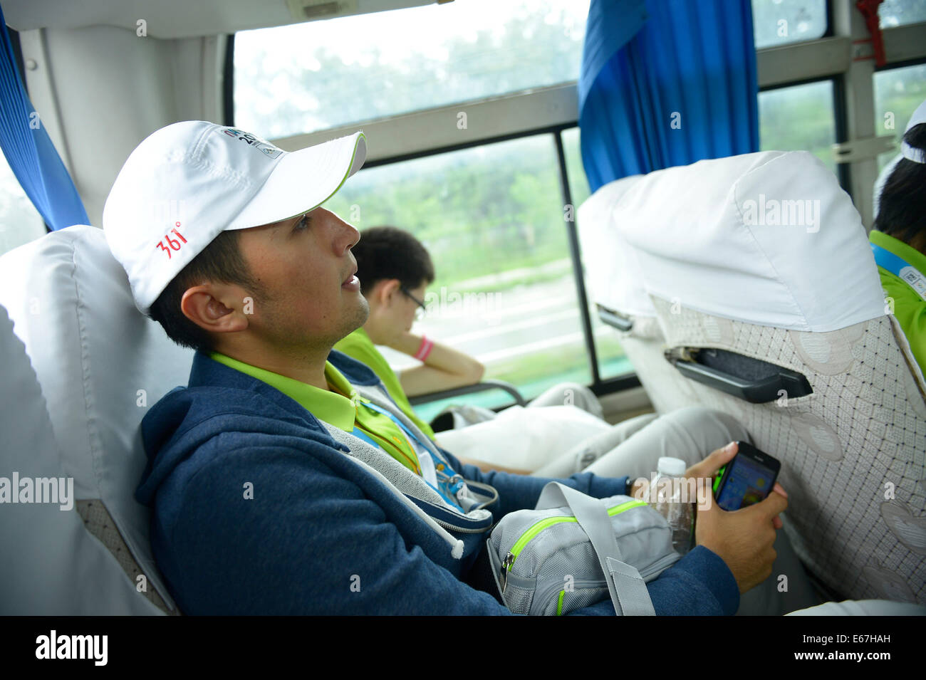 (140817) -- NANJING, Aug. 17, 2014 (Xinhua) -- Medeu Askhatuly takes the shuttle bus back to school after work during Nanjing 2014 Youth Olympic Games on Aug. 17, 2014.       21-year-old Medeu Askhatuly from Kazahkstan works as a volunteer of language service for cycling event during the Nanjing 2014 Youth Olympic Games. He is a senior student majoring in International Economics and Trade in Nanjing University of Information Science and Technology and is fluent in Kazakh, Russian, English and Chinese. He came to China with his father when he was a child and became fascinated by Chinese culture Stock Photo