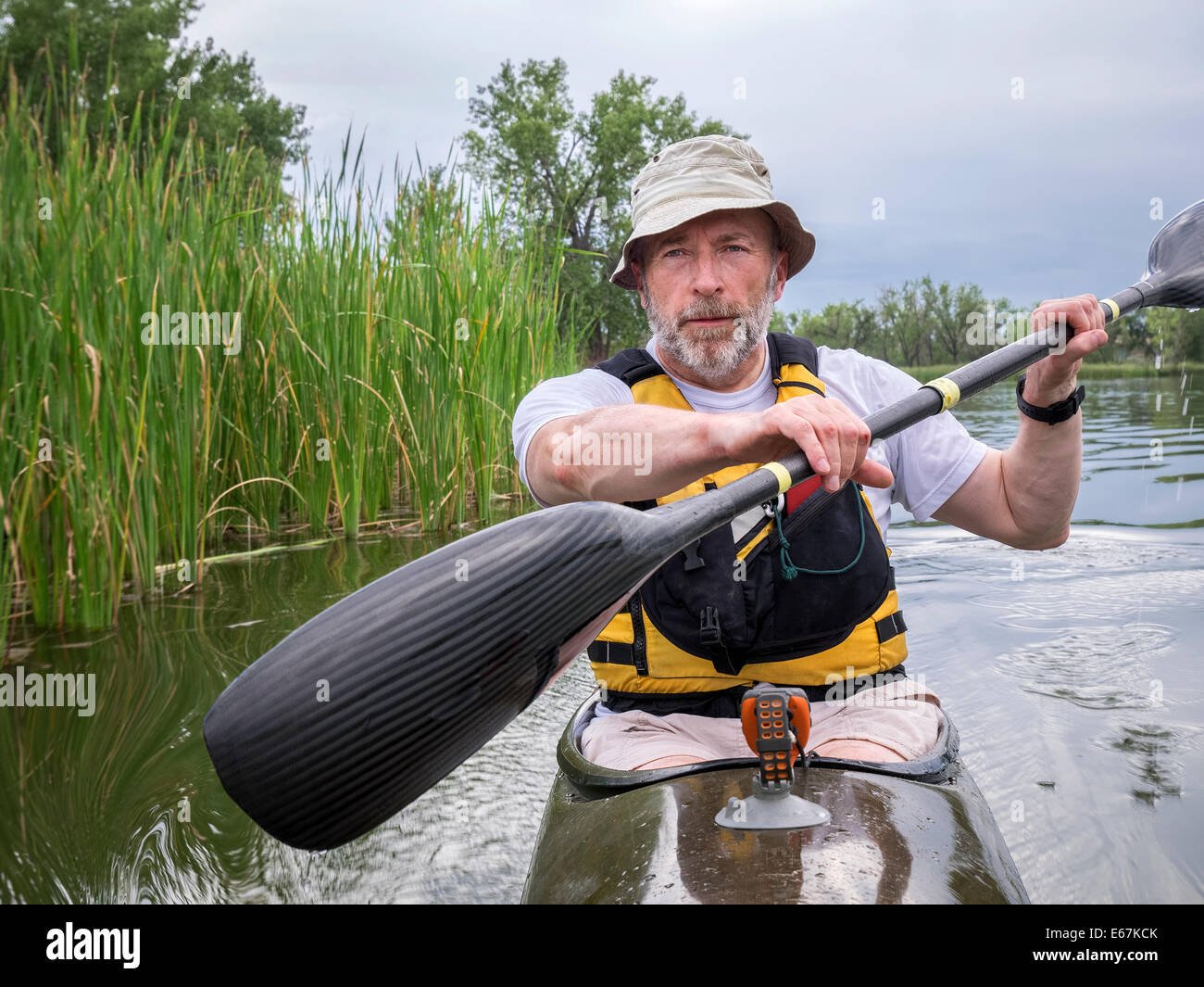 senior male paddler training in a narrow fast racing kayak on a lake in Colorado Stock Photo