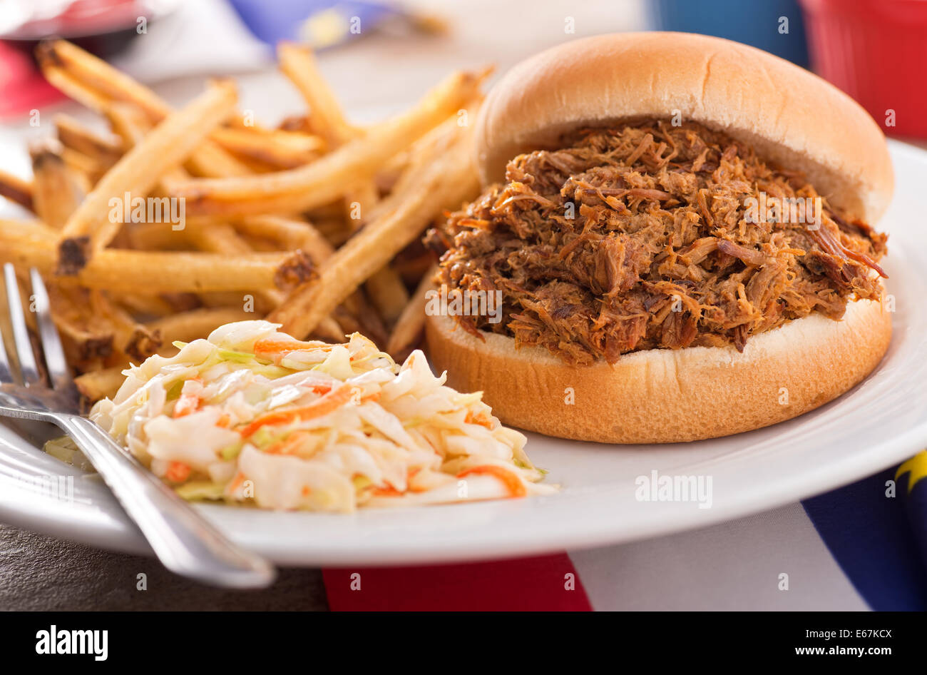 A delicious barbecued pulled pork sandwich with coleslaw and french fries. Stock Photo