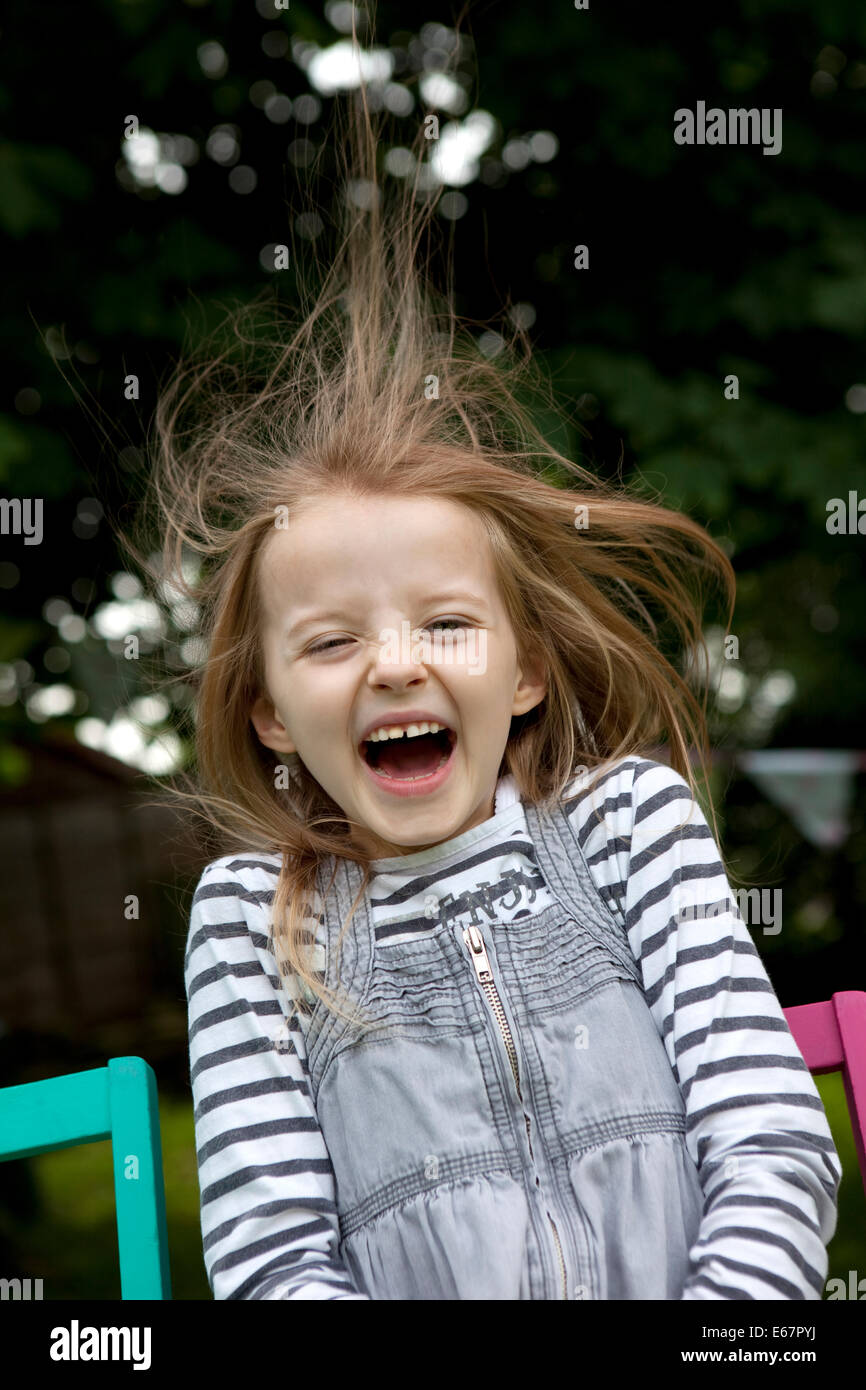 Child laughing and caught by surprise as a breeze blows her hair Stock Photo