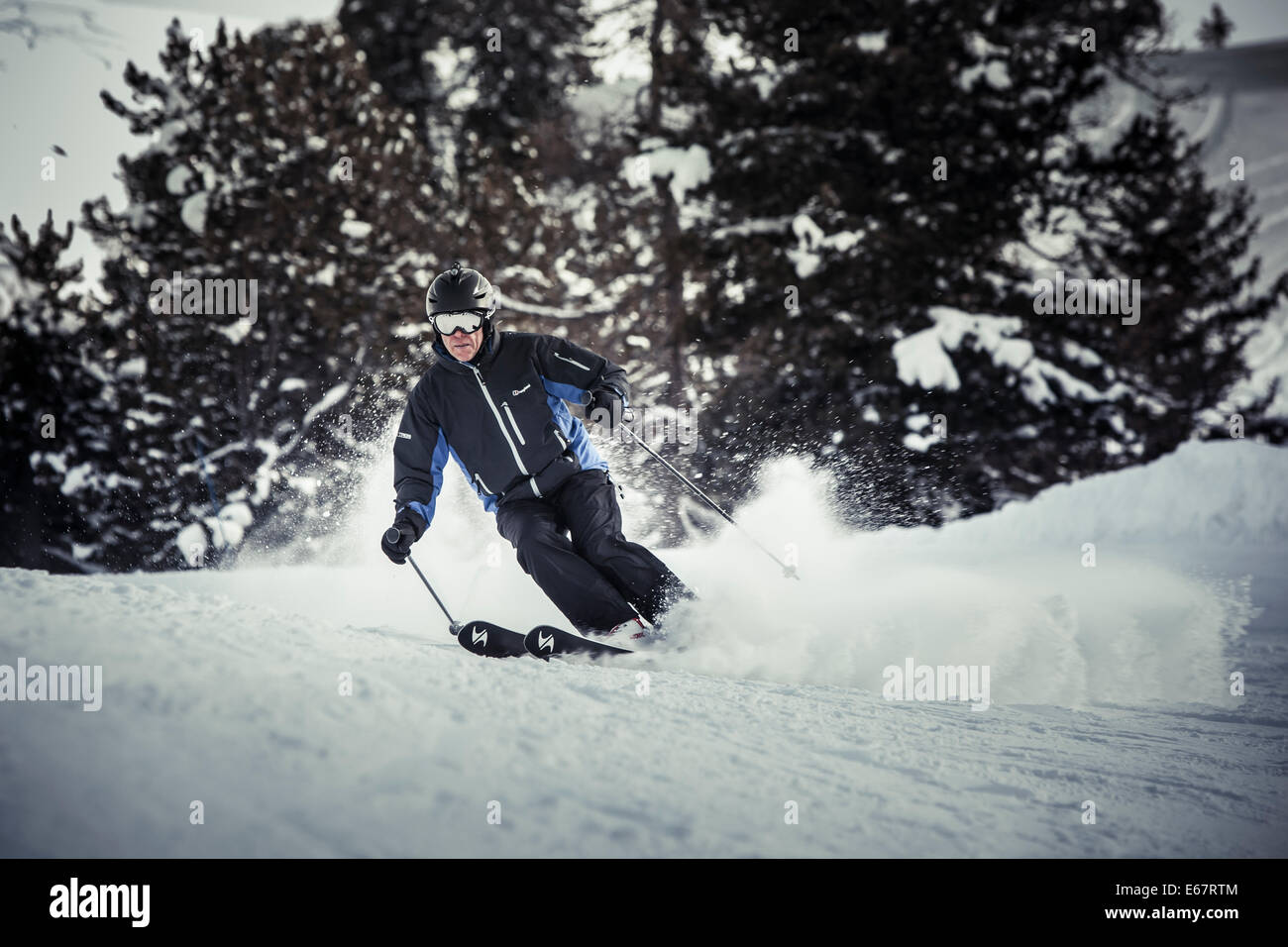 Skier wearing a black helmet with a helmet cam and goggles throws up a