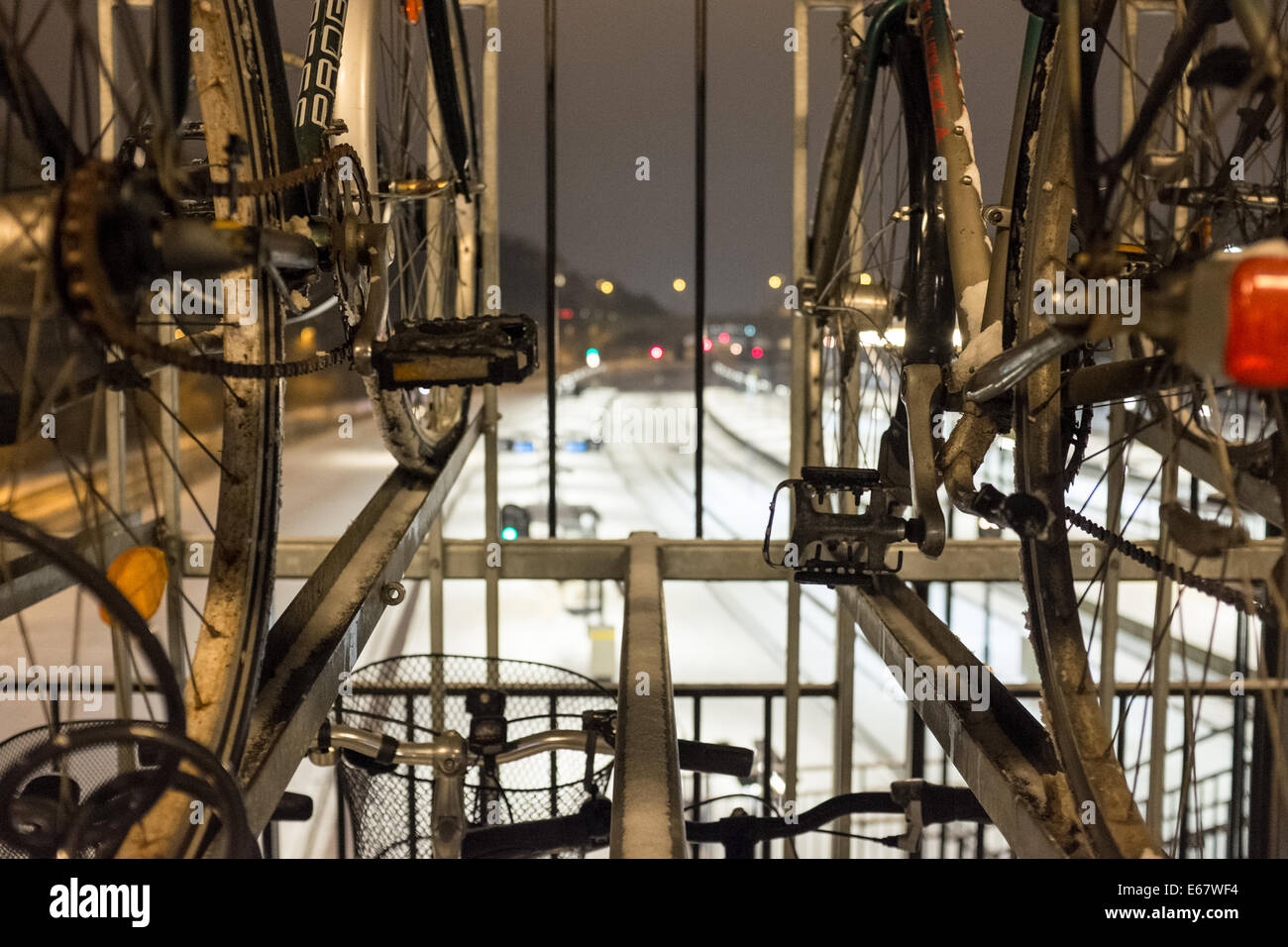 Detail of the pedals and chain of bikes parked over the train lines covered with snow in Aarhus, Denmark, Europe Stock Photo