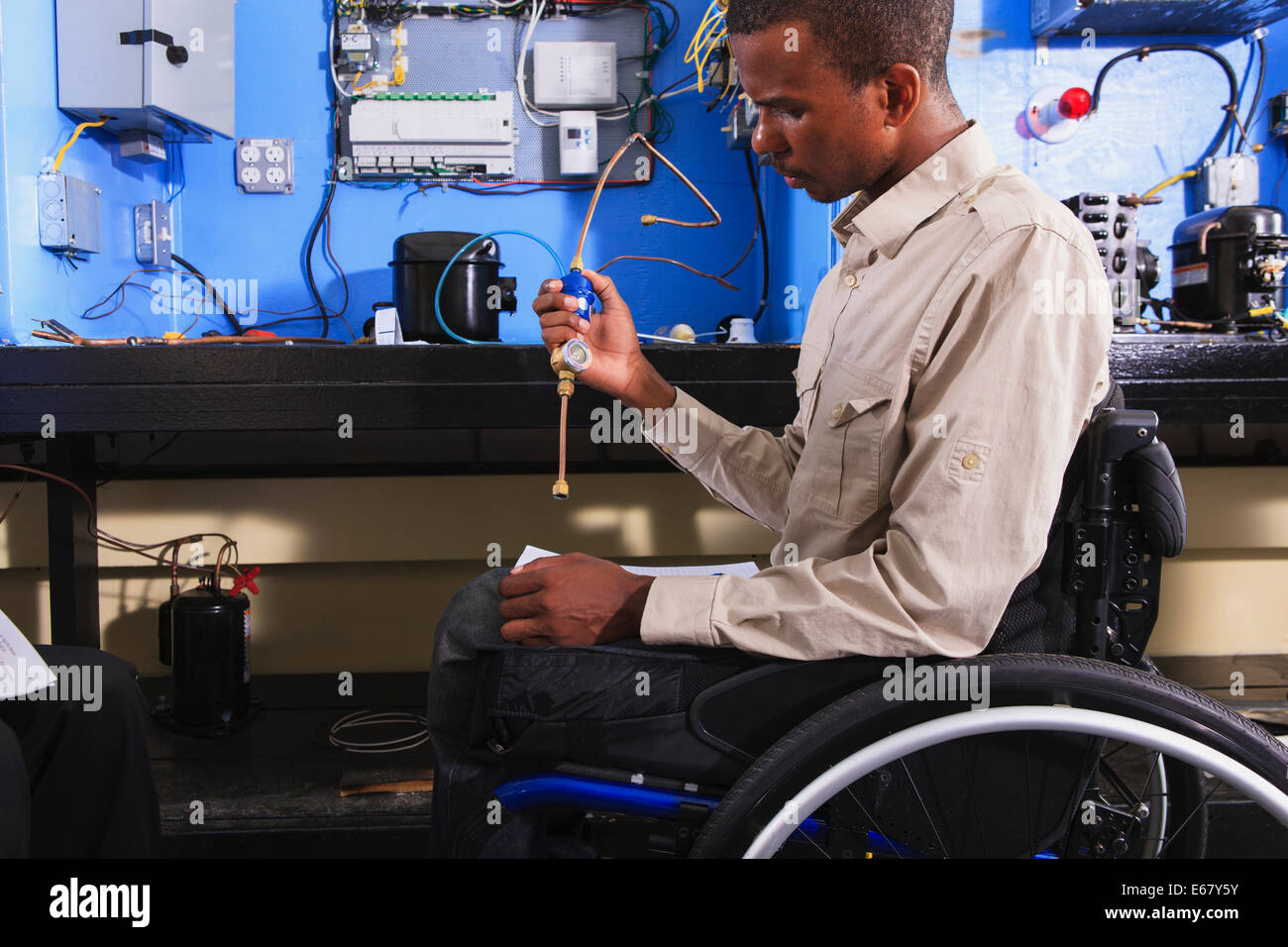 Student in wheelchair examining air conditioner high pressure line in