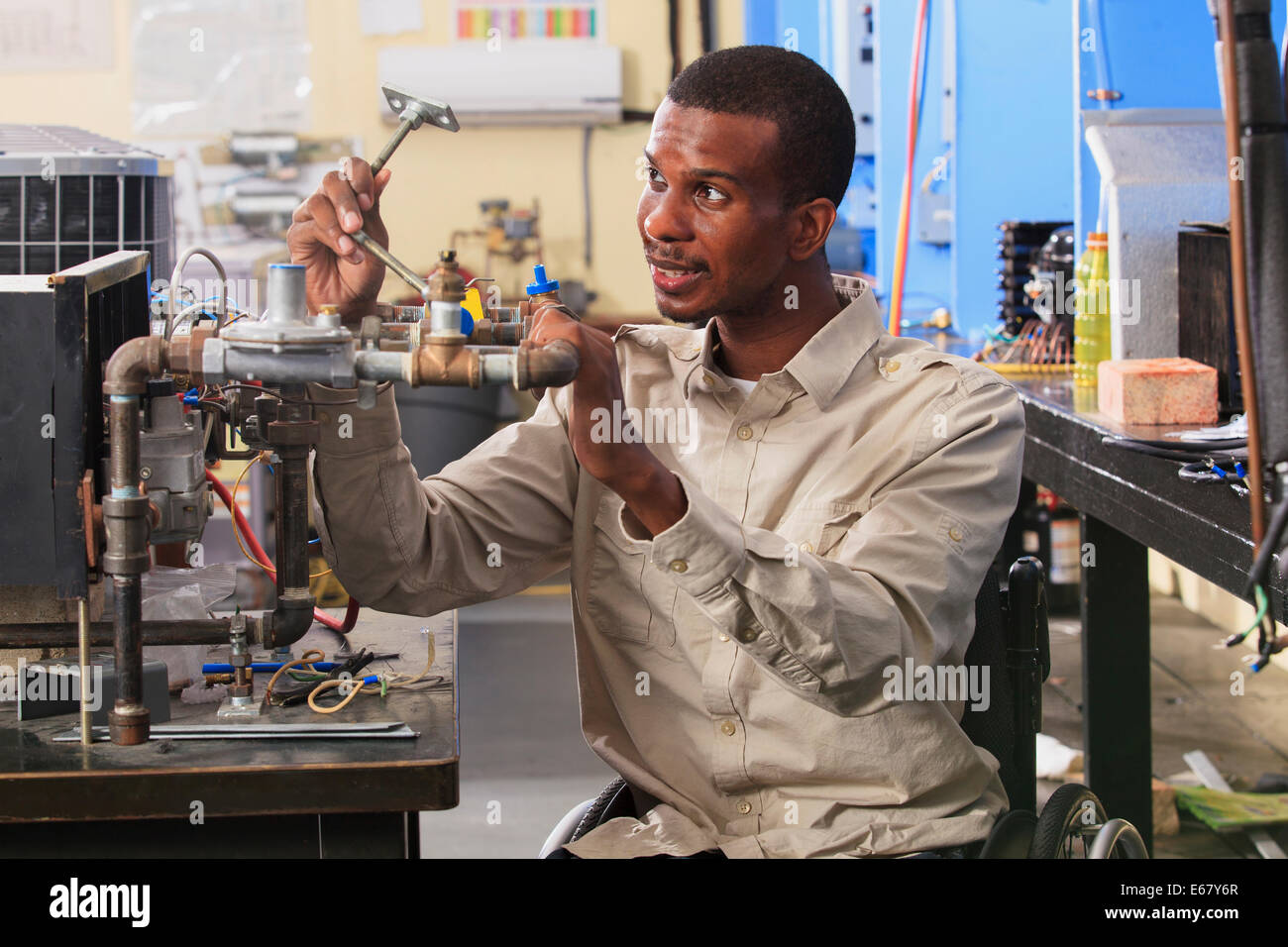 Student in wheelchair examining furnace ignitor in HVAC classroom Stock Photo