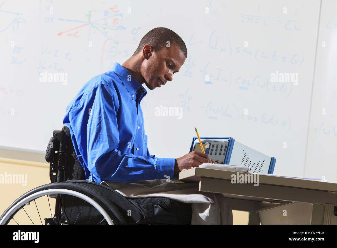 Engineering student in wheelchair from Spinal Meningitis recording measurements from an LCR impedance meter Stock Photo