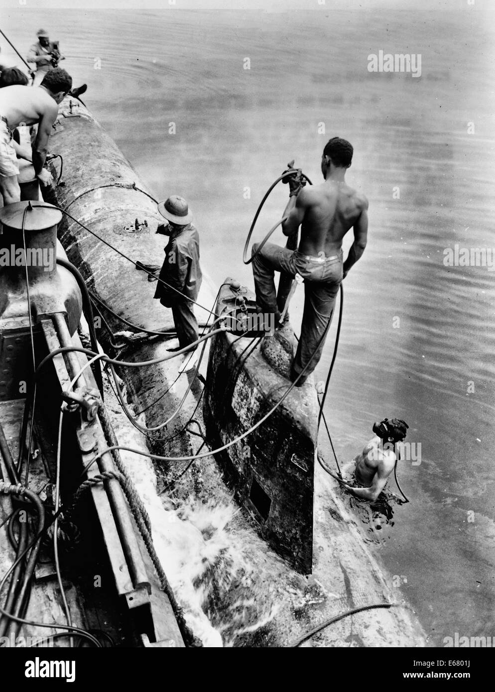 Divers and crewmen of the U.S. Navy seagoing tug Ortolan fasten midget Japanese submarine to the side of their ship, July 17, 1943. Pearl Harbor, Hawaii Stock Photo