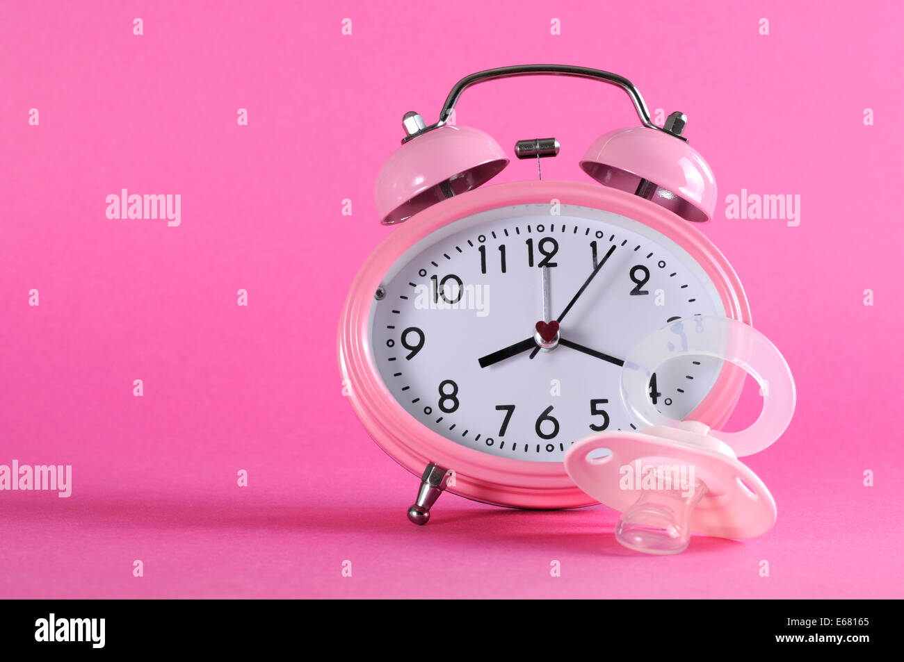 Pretty pink vintage retro style alarm clock with baby dummy pacifier on