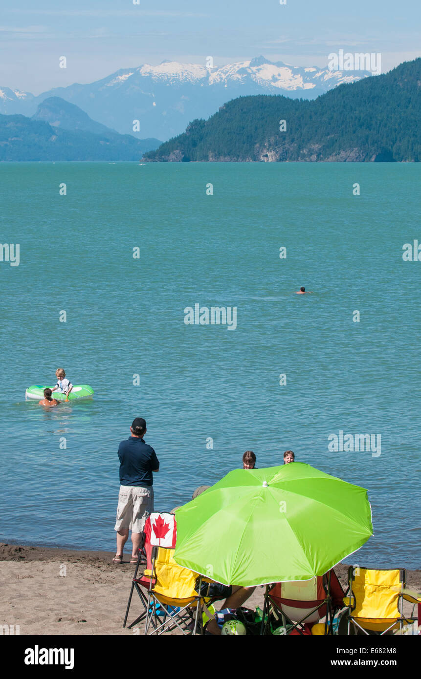 Green beach umbrella family on beach at Harrison Lake, Harrison Hot Springs resort, British Columbia, Canada. Stock Photo