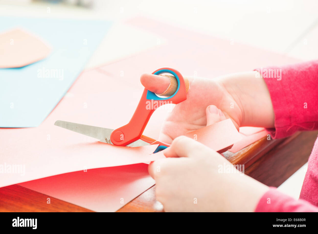 Little girl cutting paper with scissors Stock Photo