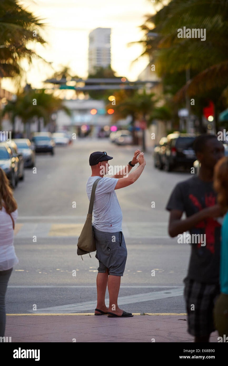 Miami in Florida USA a tourist captures his holiday snap shot picture on Ocean Drive at sunset. Stock Photo