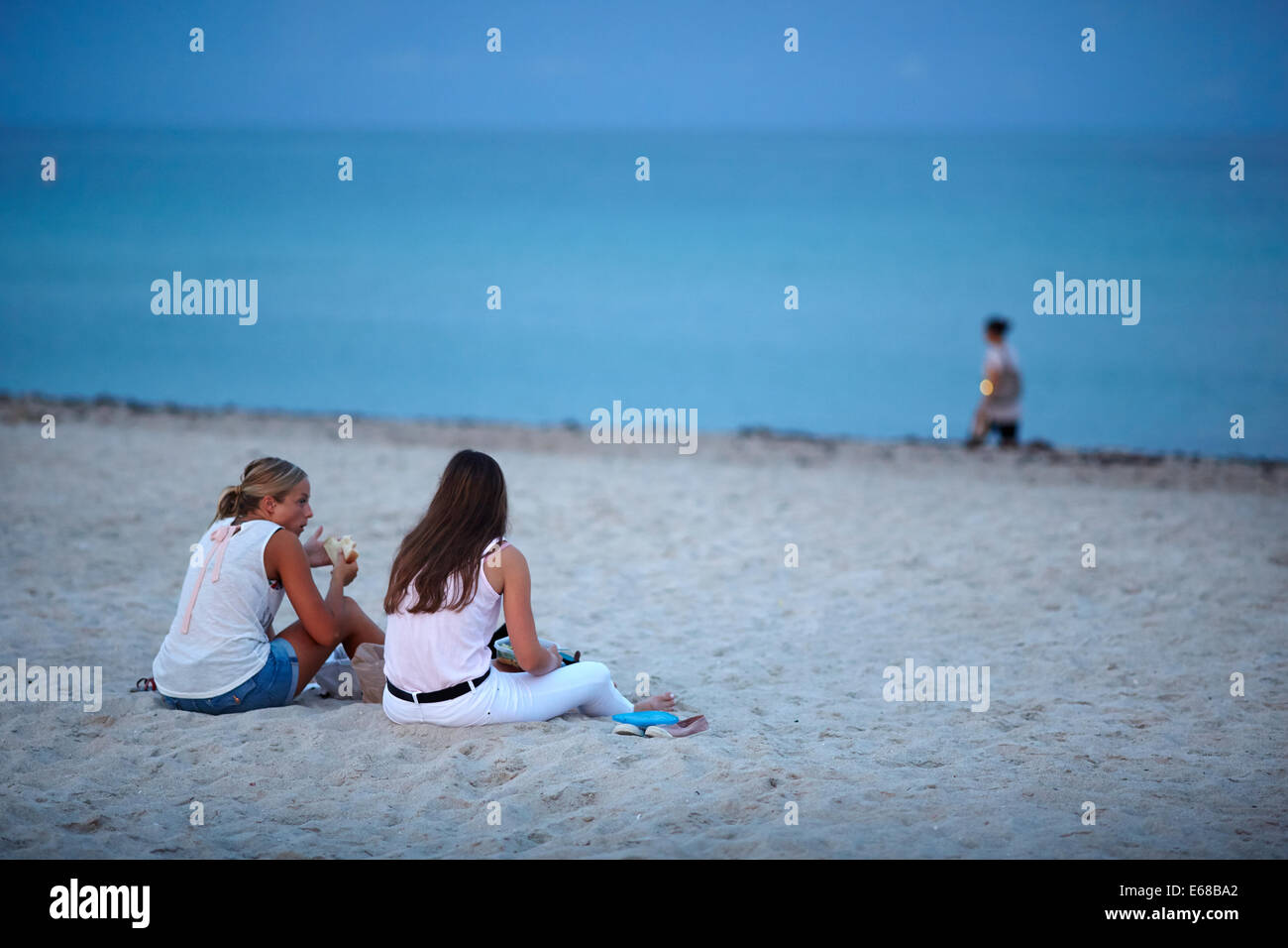 South Beach Ocean Drive  Miami in Florida USA, 2 girls sat on the beach at dawn Stock Photo