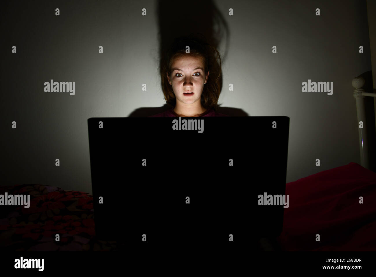 Computer laptop being used by a child in her bedroom, teenage girl using a computer laptop alone in her room Stock Photo