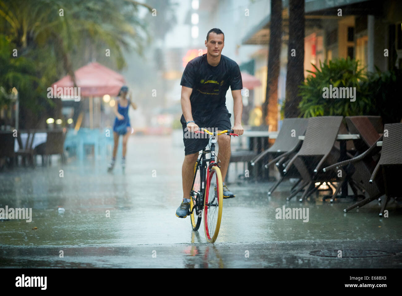 A man cycles through the street on his colorful bike Stock Photo