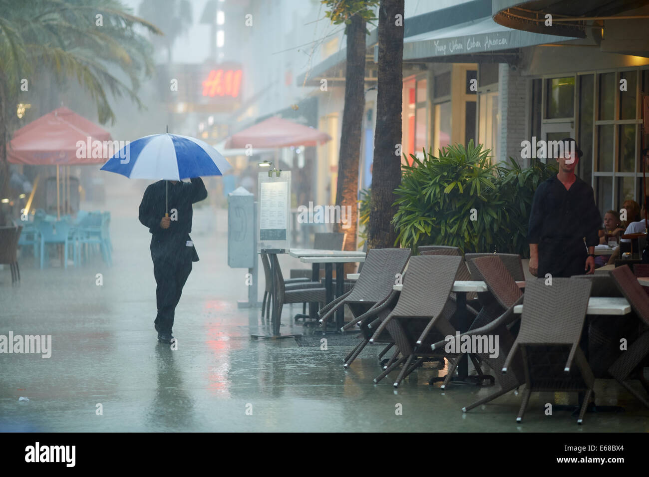 tropical rain storm brings the shops and restaurants to a stop, pictured a waiter still working be spite the rain Stock Photo