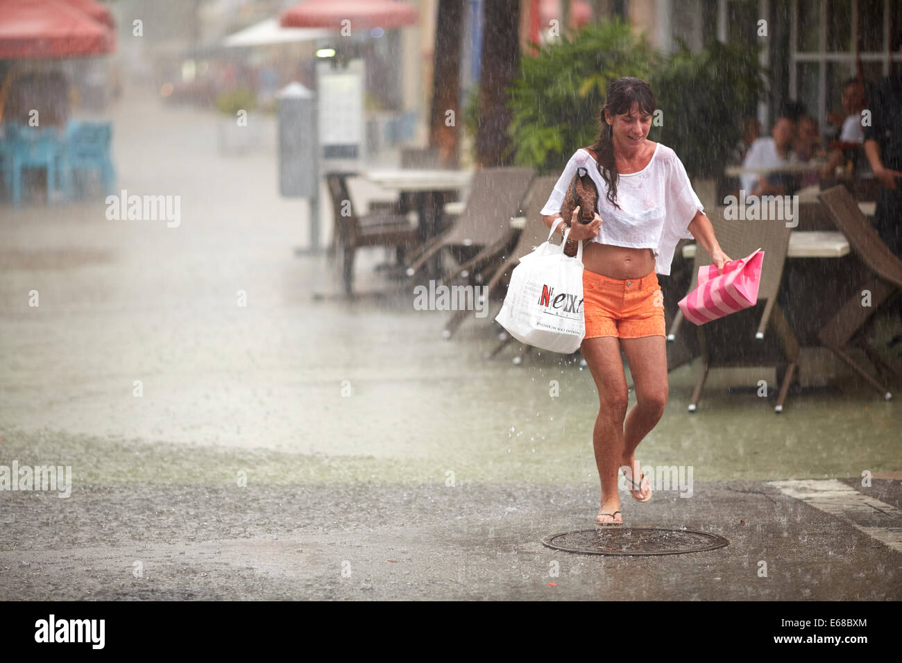 Woman carrying shopping caught out by Miami tropical storm Stock Photo