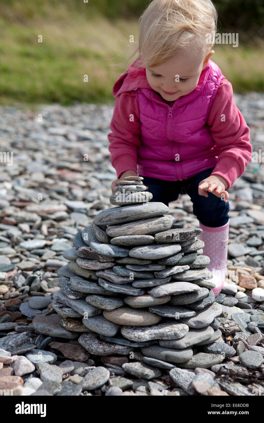 Young child stacking rocks on a pebble beach Stock Photo Alamy