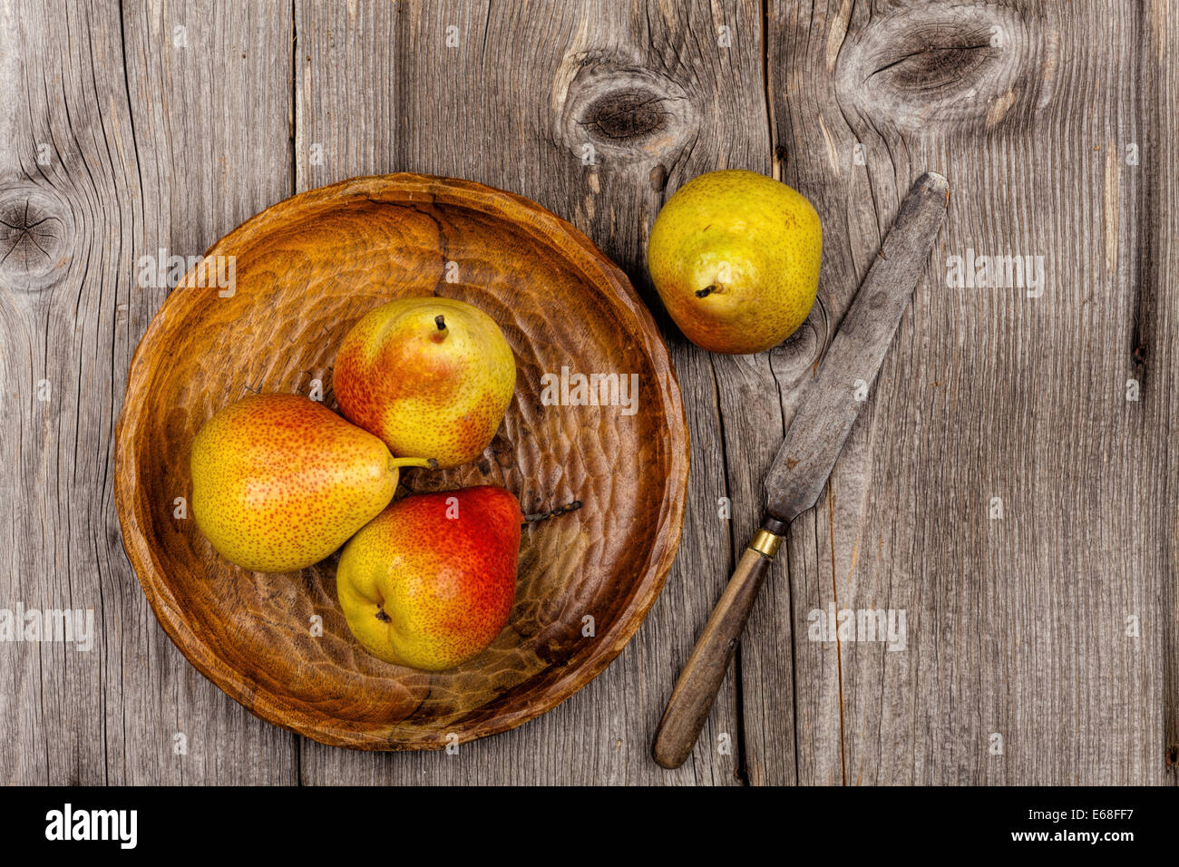 Pears on a wooden plate with a knife on an old rustic wooden table in country style Stock Photo