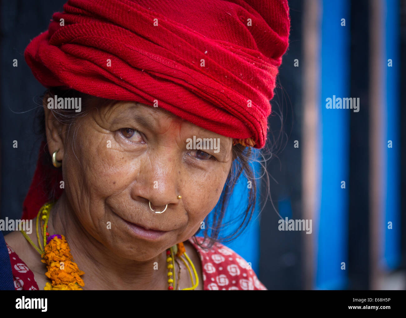 Portrait of a colorful female beggar, wearing a red headscarf and a nose ring, at a spiritual hindu market in Kathmandu, Nepal. Stock Photo