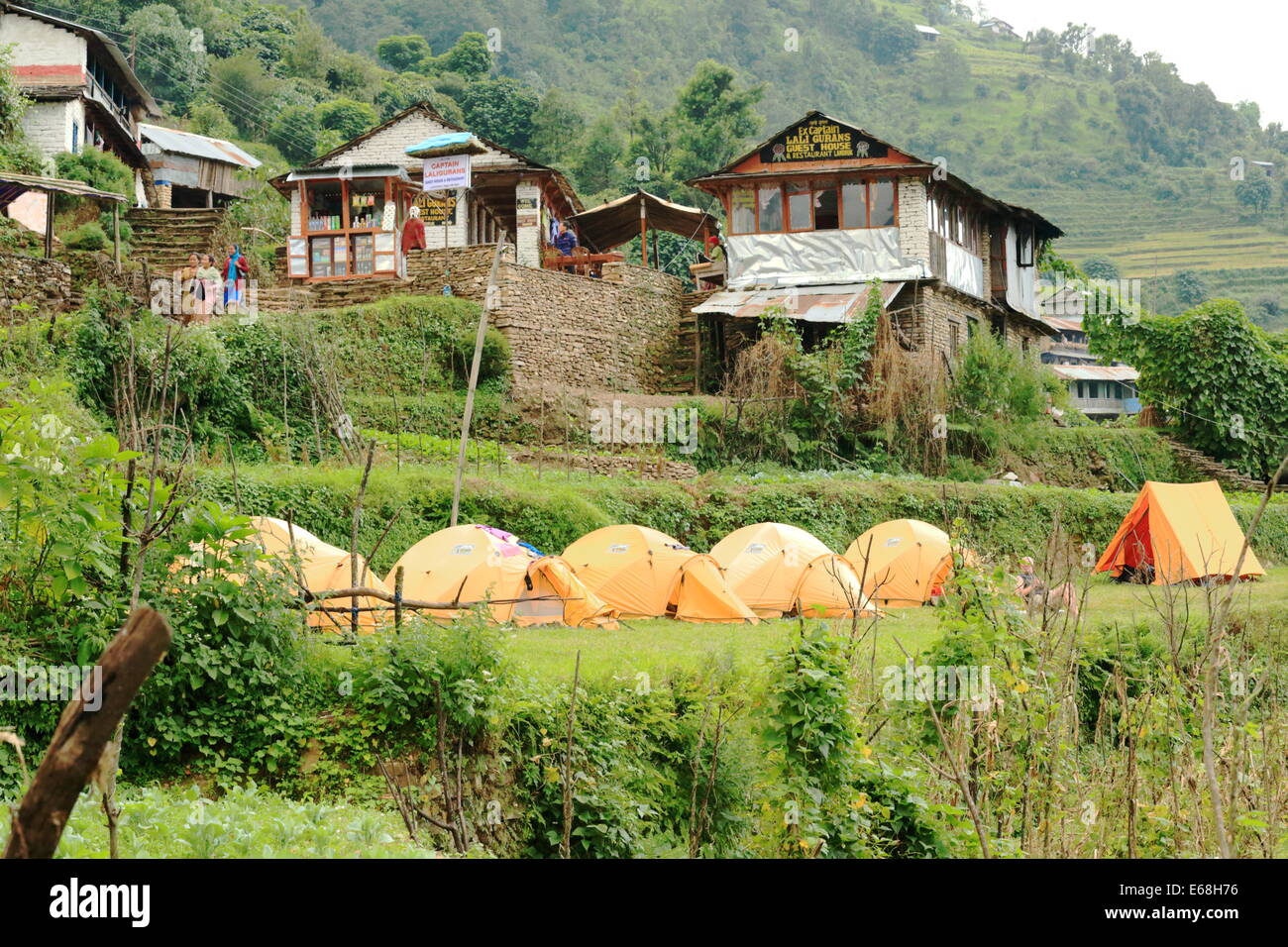 LANDRUK, NEPAL - OCTOBER 9: A tourist group camps with their yellow tents on a campsite outside Lali Gurans Guest House on Octob Stock Photo