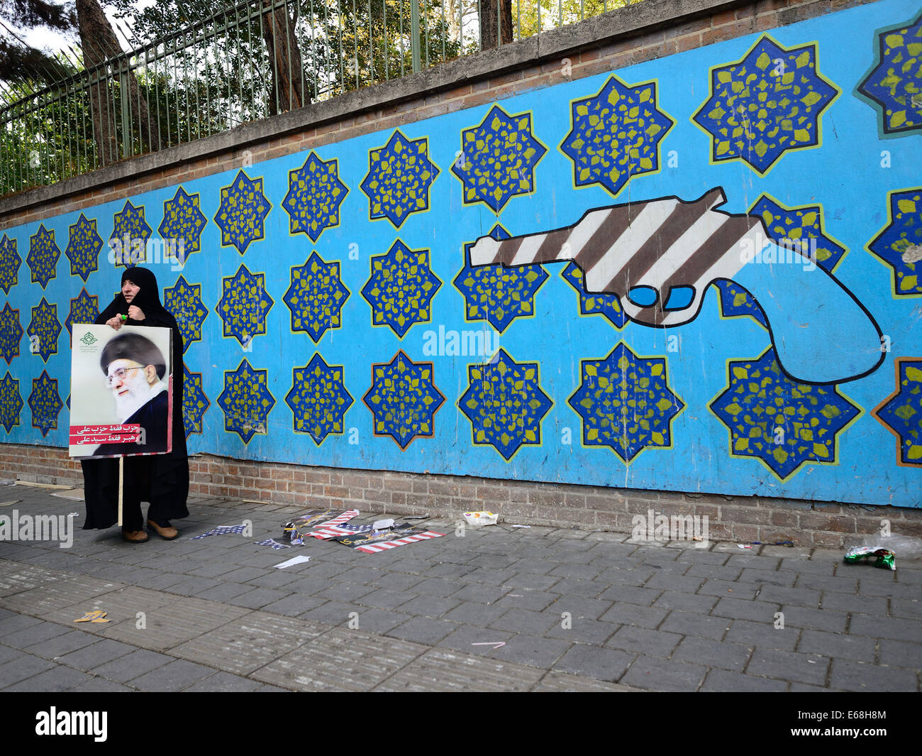 An Iranian woman walks past an anti-U.S.mural, painted on the wall of the former U.S. Embassy, Stock Photo