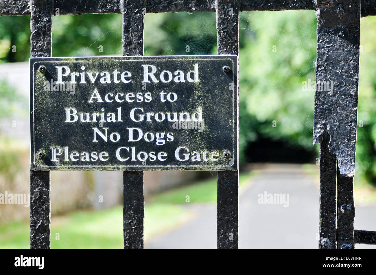 Sign on the gate into a graveyard: 'Private Road.  Access to Burial Ground. No Dogs. Please Close Gate' Stock Photo