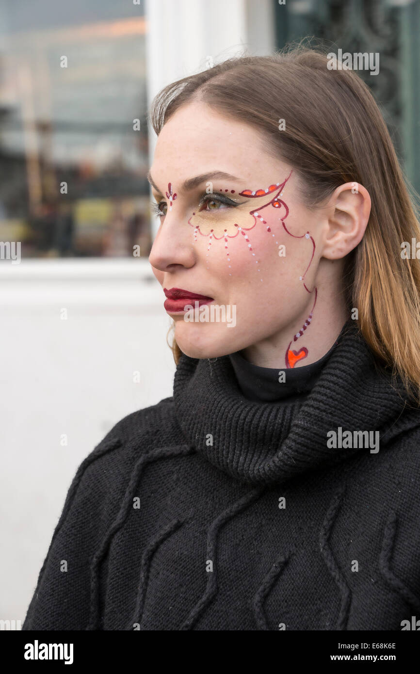 Young woman face painter during Carnival shows off her design on the waterfront in the Castello District of Venice. Stock Photo