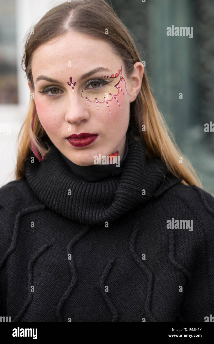Young woman face painter during Carnival shows off her design on the waterfront in the Castello District of Venice. Stock Photo