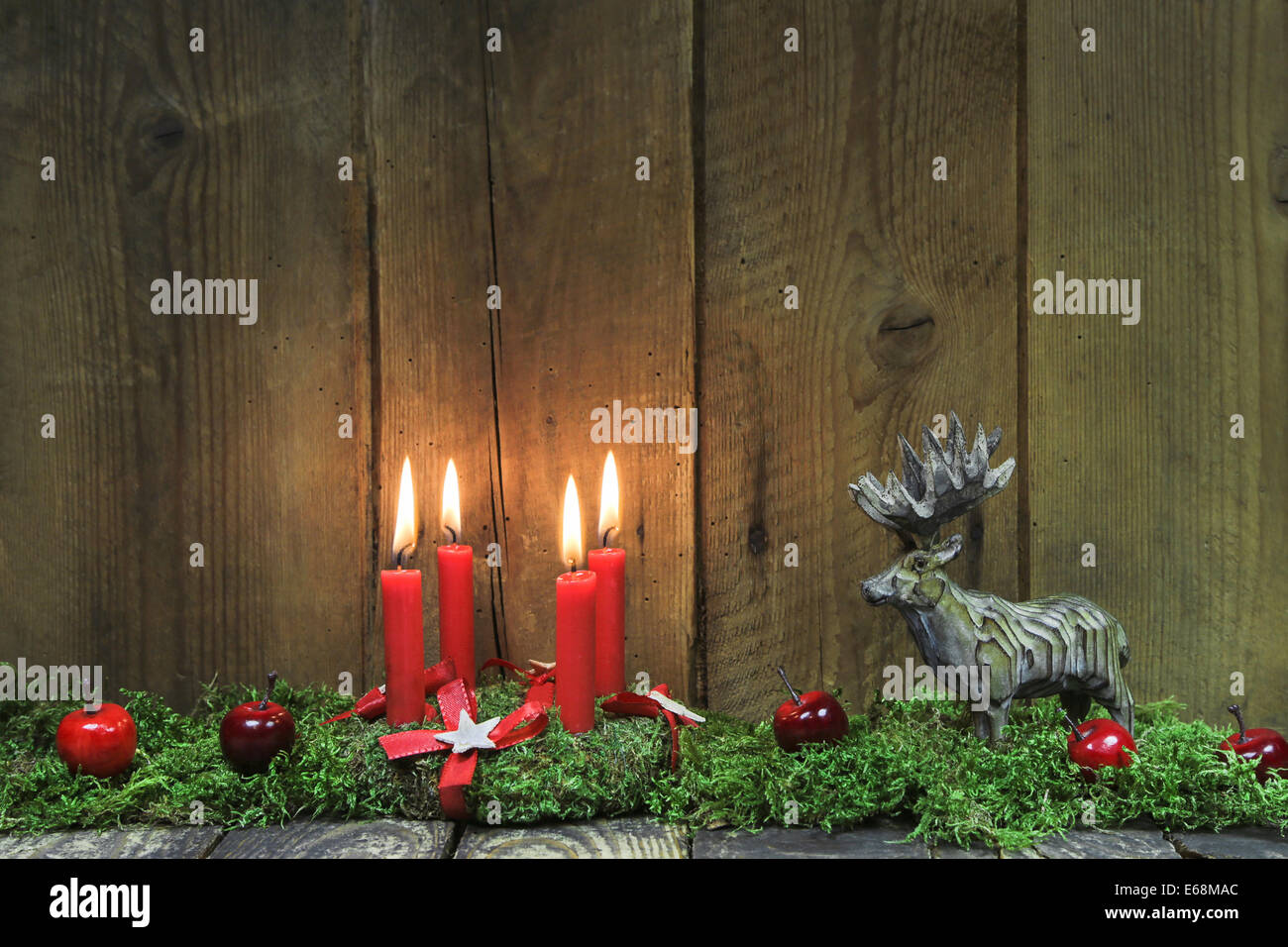 Classic: Four red burning christmas candles on wood background with deer. Stock Photo