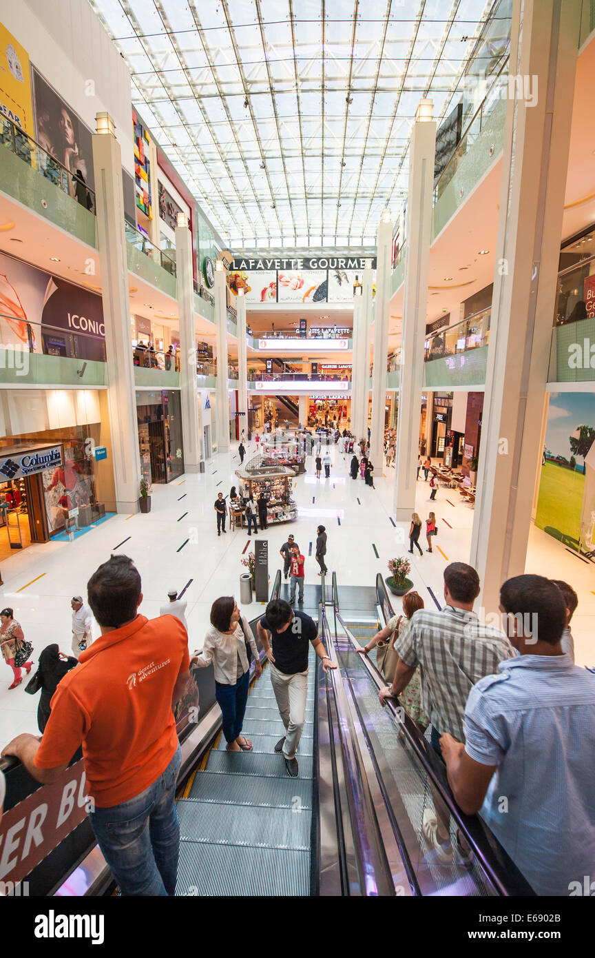 Shoppers on escalator in multi floor retail shops shoppers shopping at Mall of the Emirates, Dubai, United Arab Emirates UAE. Stock Photo