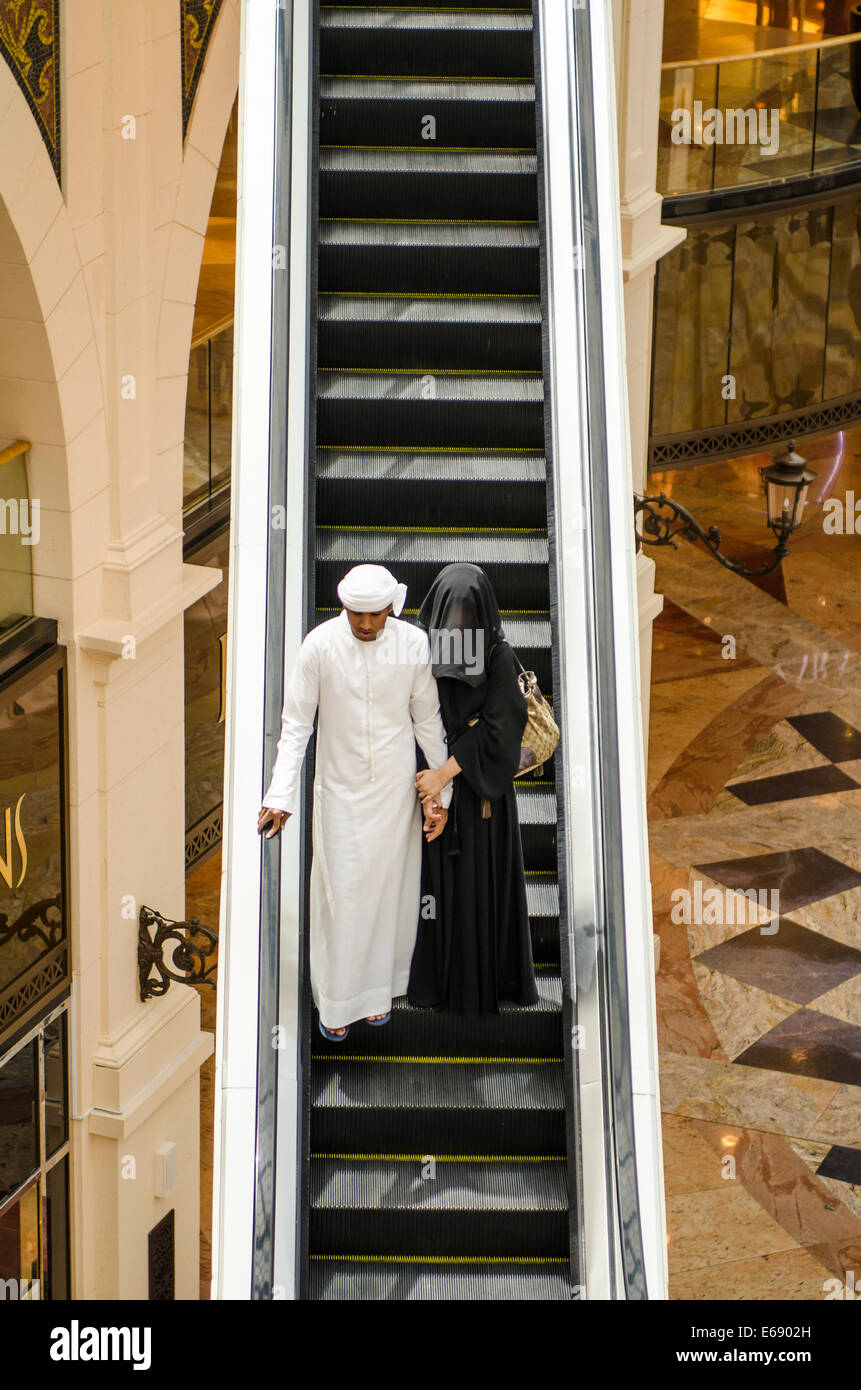 Arab Islamic muslim husband and wife couple traditional on escalator in Mall of the Emirates, Dubai, United Arab Emirates UAE. Stock Photo
