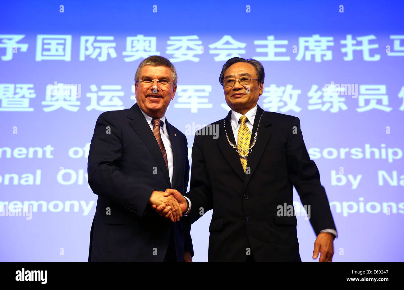 Nanjing, China's Jiangsu Province. 19th Aug, 2014. President of International Olympic Committee Thomas Bach(L) presents Olympic medal of honor to Wen Guogang, the coach of Olympic fencing champion Luan Jujie in Nanjing, capital of east China's Jiangsu Province, on Aug. 19, 2014. Credit:  Xu Lijun/Xinhua/Alamy Live News Stock Photo